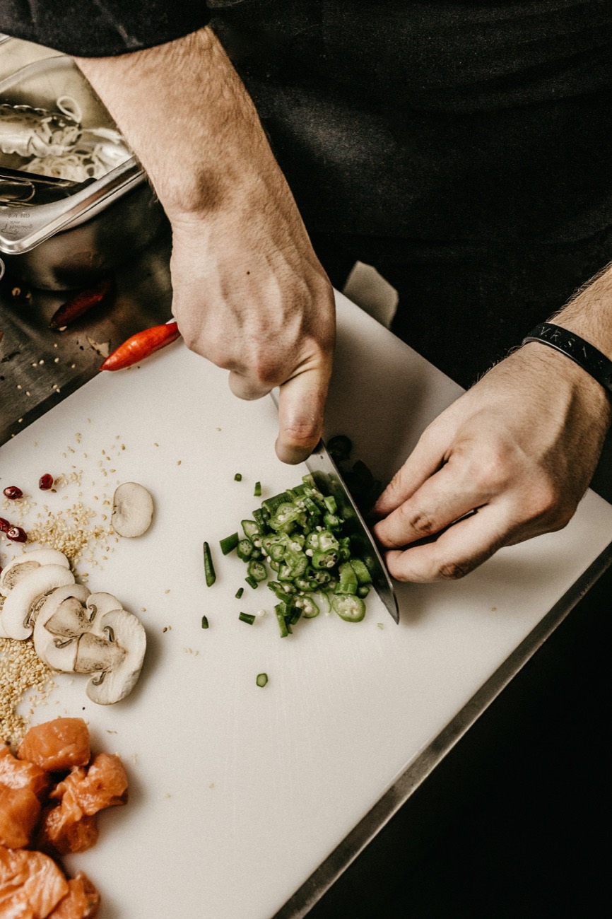 Manos picando chiles en la tabla, con la mise en place alrededor